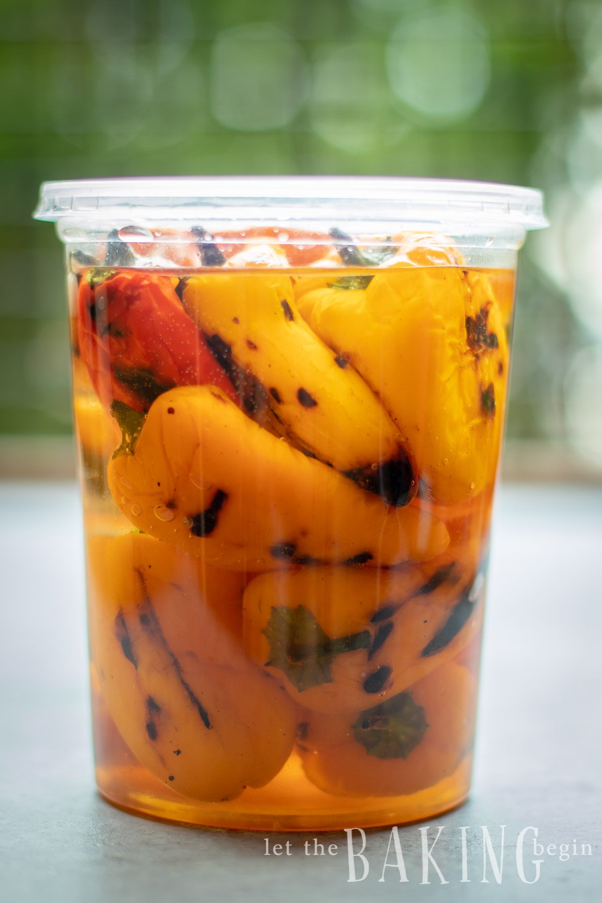 Bell peppers in a sweet marinade in a plastic container.