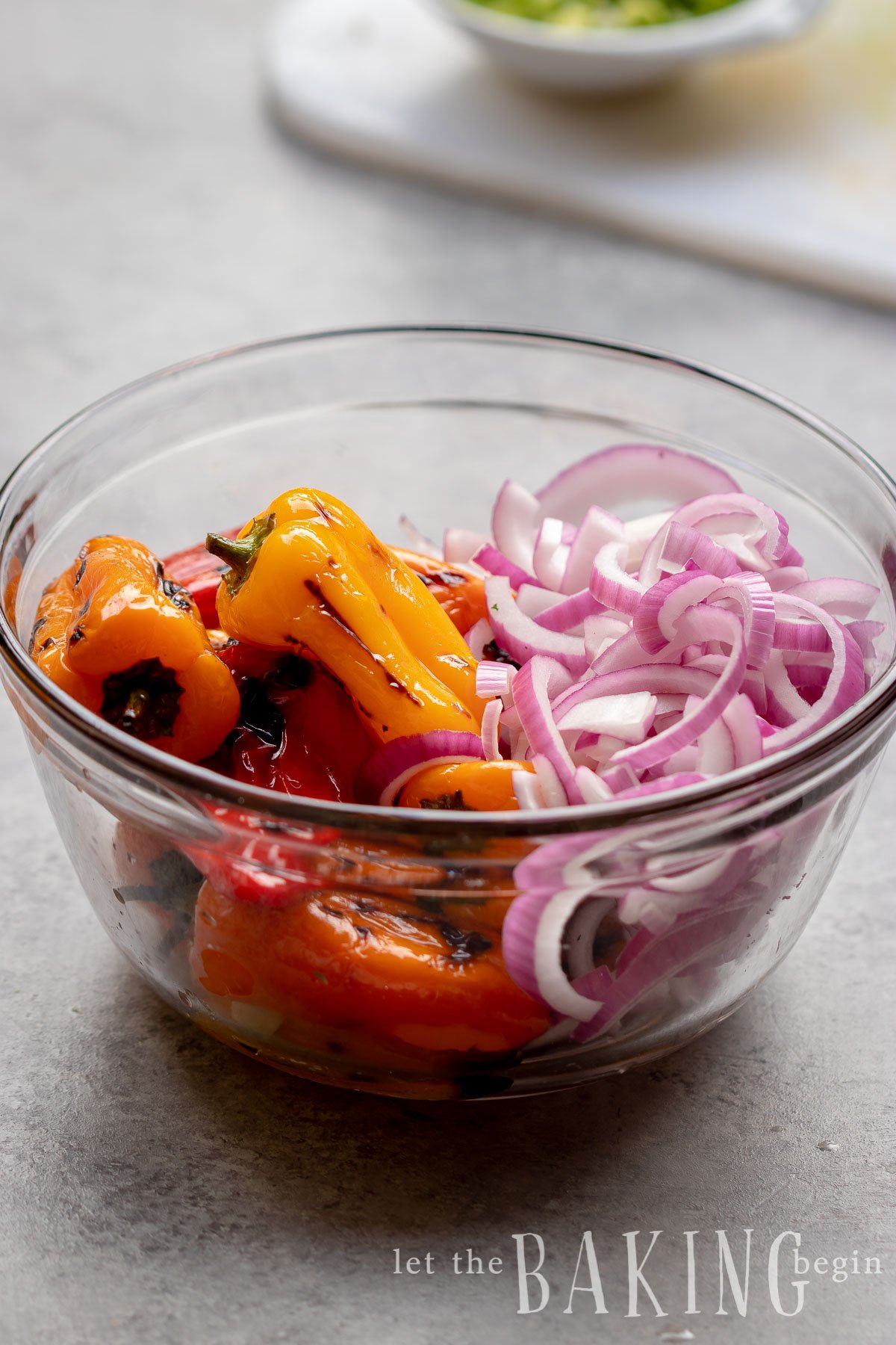 Mini bell peppers and onions in a clear bowl.