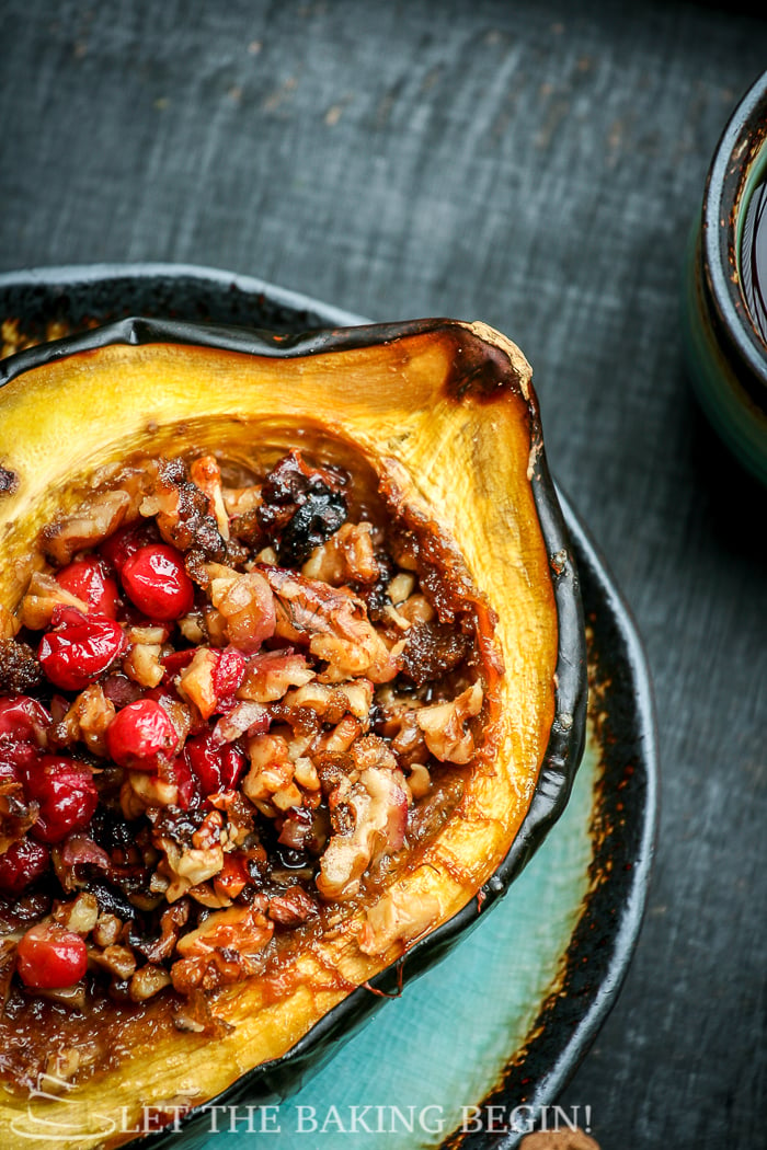 Close up picture of acorn squash stuffed with cranberries and walnuts on a plate. 