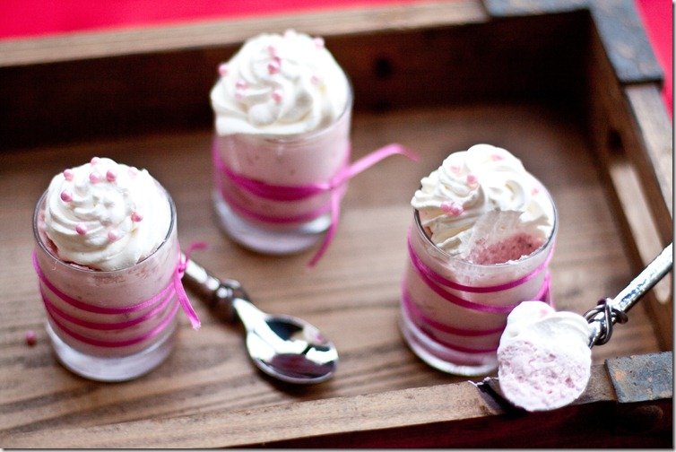 No bake strawberry cheesecake in glass cups on a wooden tray with spoons.