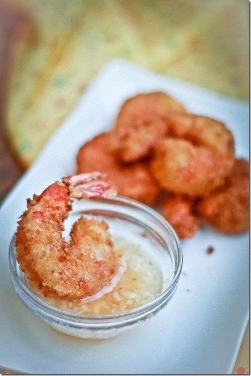 Deep fried prawns dipped in garlic dip on a white decorative tray.