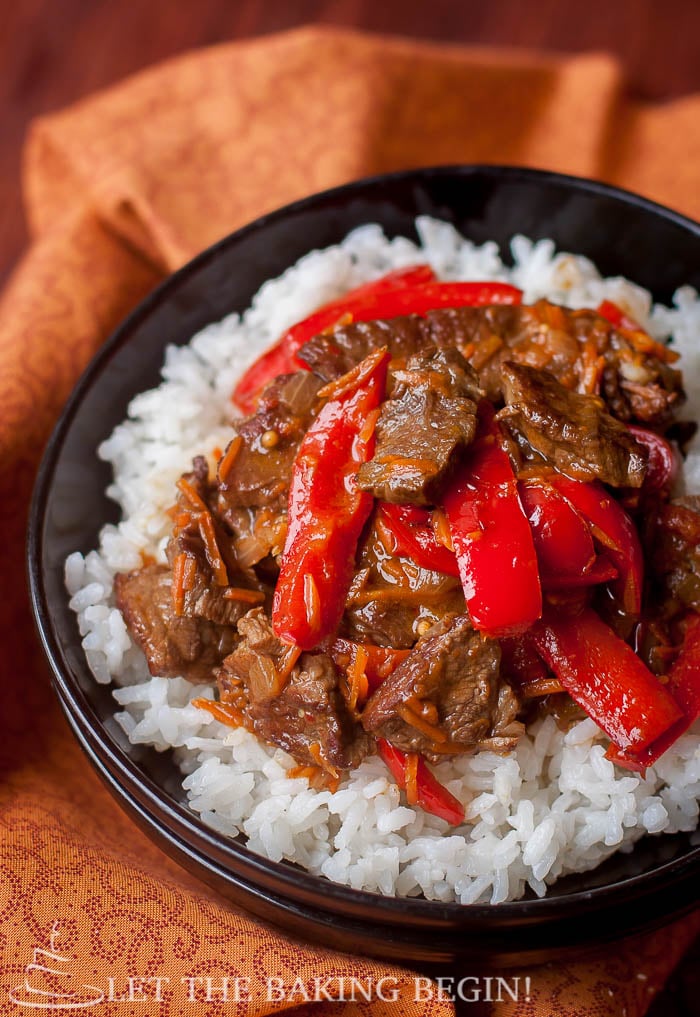 A bowl of white rice and spicy beef and bell peppers.