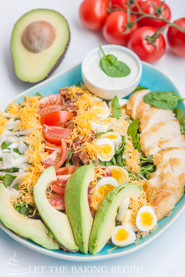 Cobb salad in a decorative bowl topped with all ingredients and fresh greens.