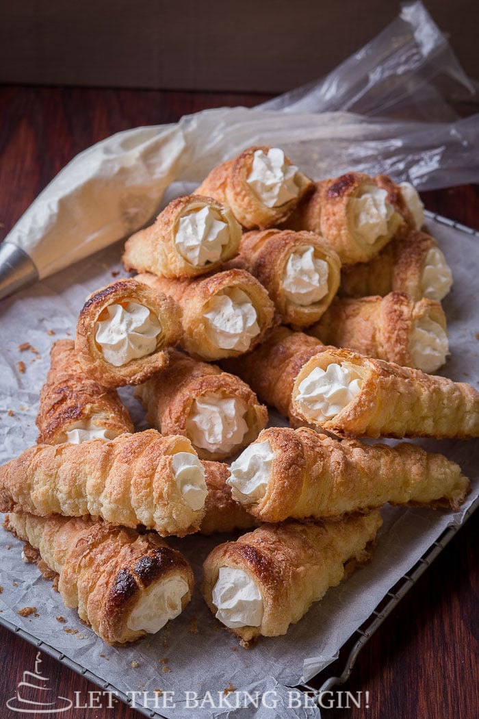 Puff Pastry Cream Horns on a baking sheet filled with whipped cream. 