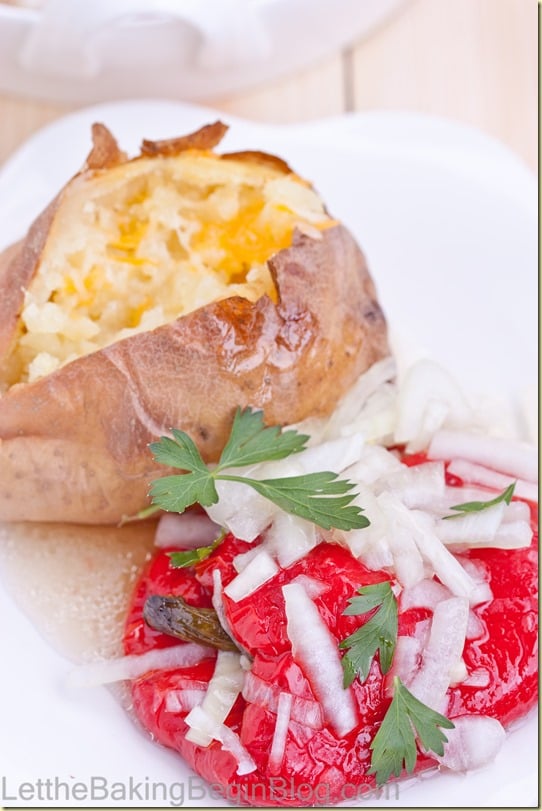 A red roasted pepper topped with sweet onion marinade sided with a baked potato on a white plate.