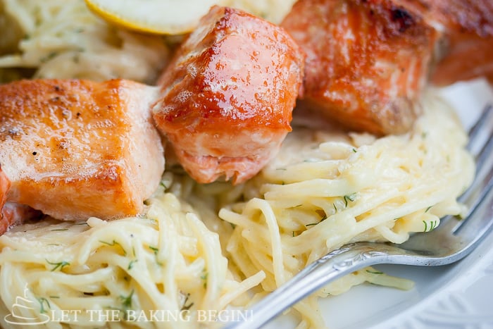 Close up picture of oven grilled salmon kabobs on top of spaghetti noodles. 