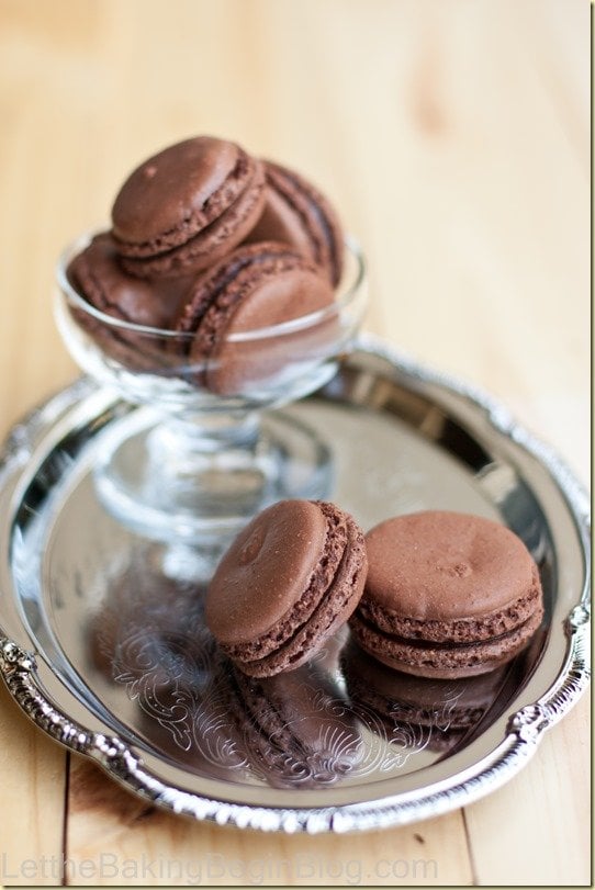 Two Dark Chocolate Truffle Macaron recipe on a tray with some in a cup.