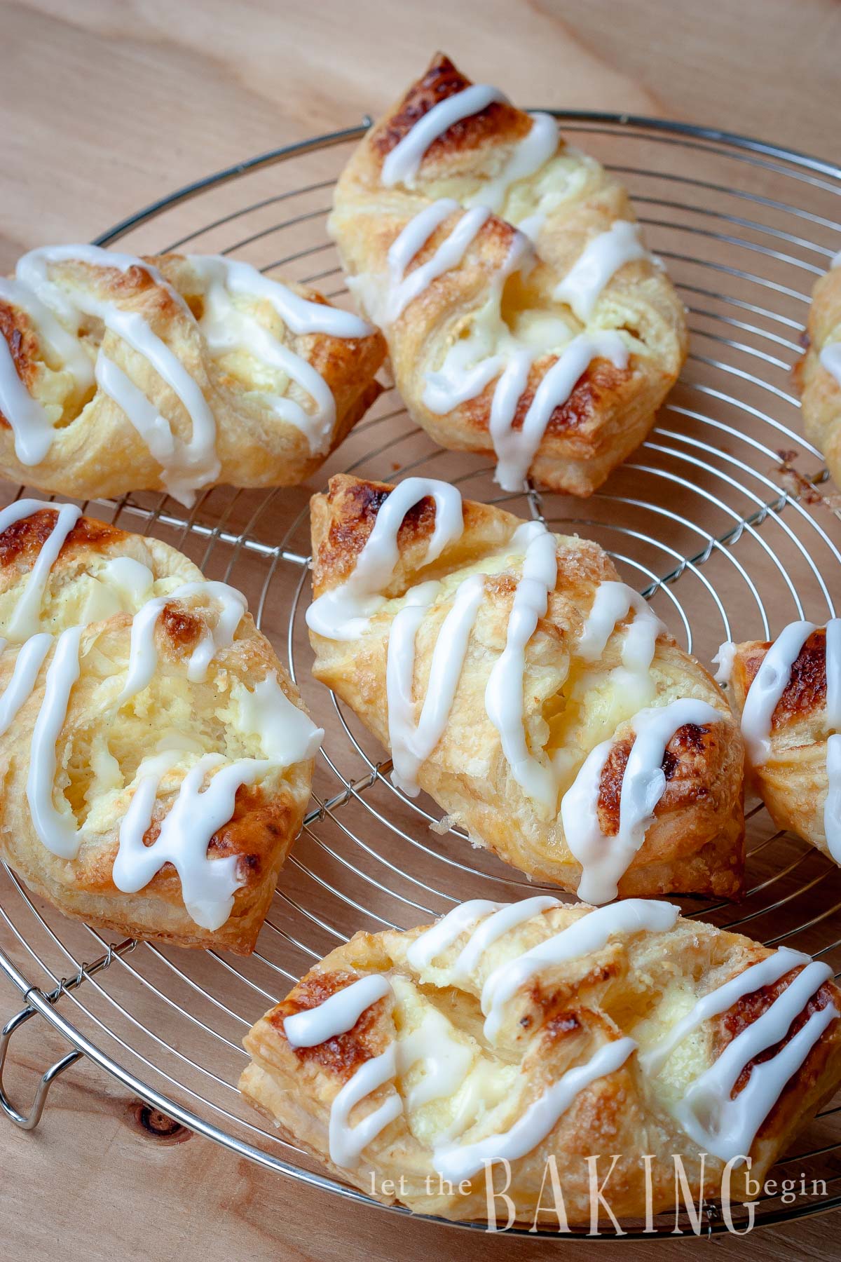 Cheesecake Danishes with lemon glaze on a cooling rack.