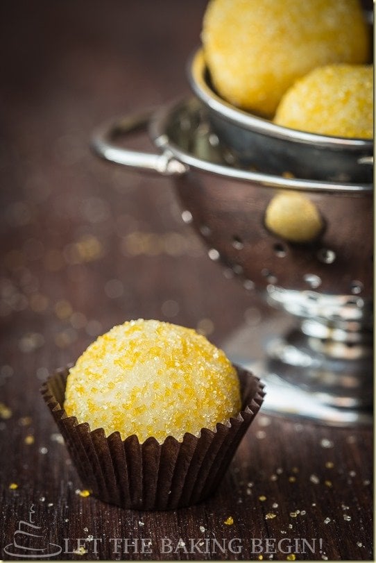 Lemon truffles in a brown liner next to a bowl of truffles/ 
