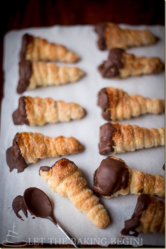 Cream horns dipped in chocolate with no filled on a parchment paper.