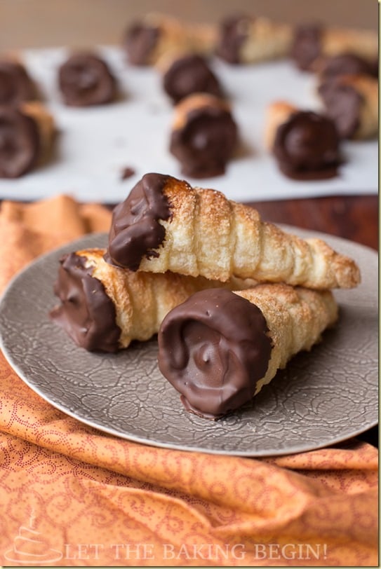 Three cream horns dipped in chocolate on a gray decorative plate.
