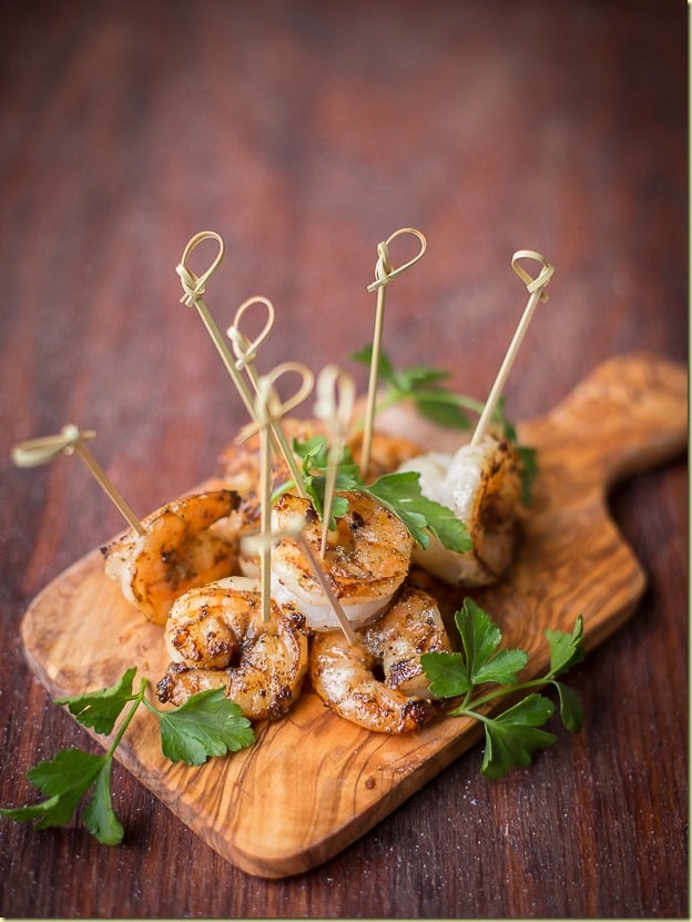 Sauteed garlic shrimp with toothpicks on a cutting board. 