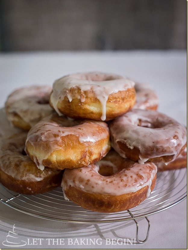 Super Soft Doughnuts with Sugar Glaze on a cooling rack stacked on top of each other.