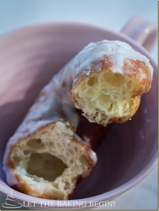 Super soft doughnut with sugar glaze in a cup opened showing the soft inside. 