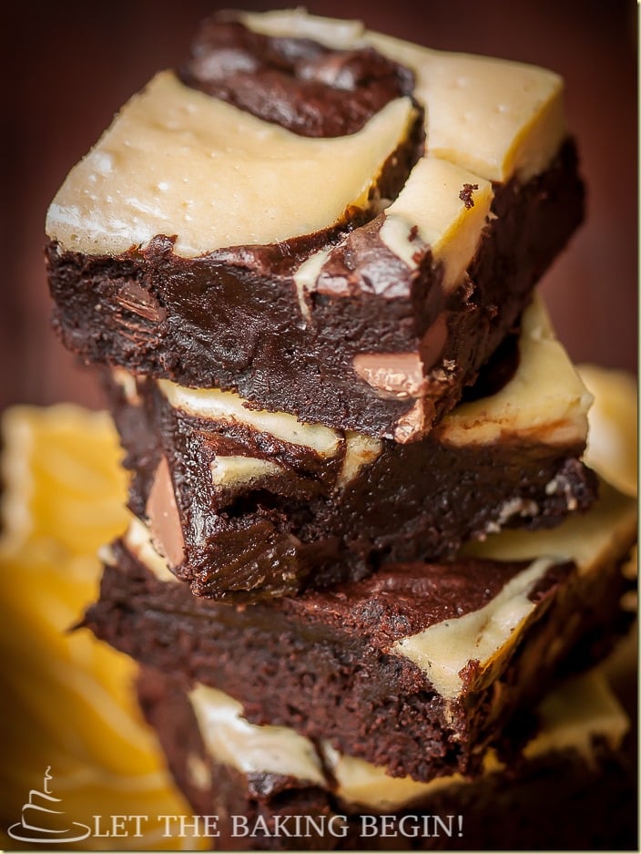 Close up photo of a tower of cheesecake brownies stacked on a plate.