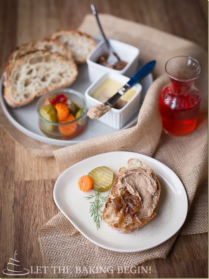 Chicken liver mousse recipe next to balsamic onions, vegetables, and bread on a white plate.