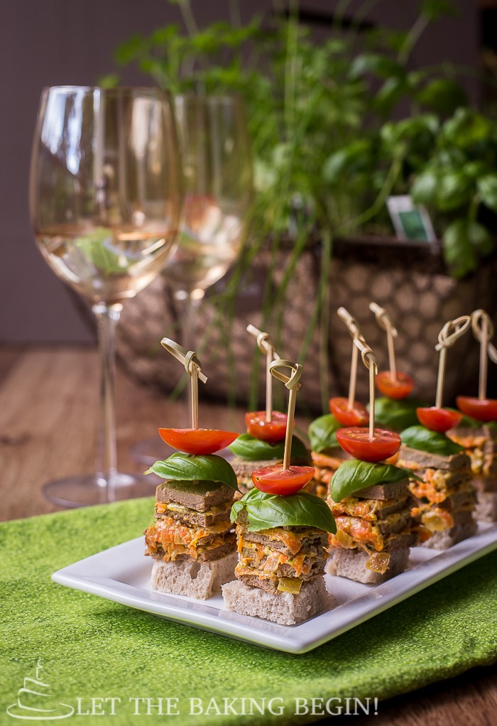 Chicken stacks with tomatoes on a decorative white plate on a green napkin.