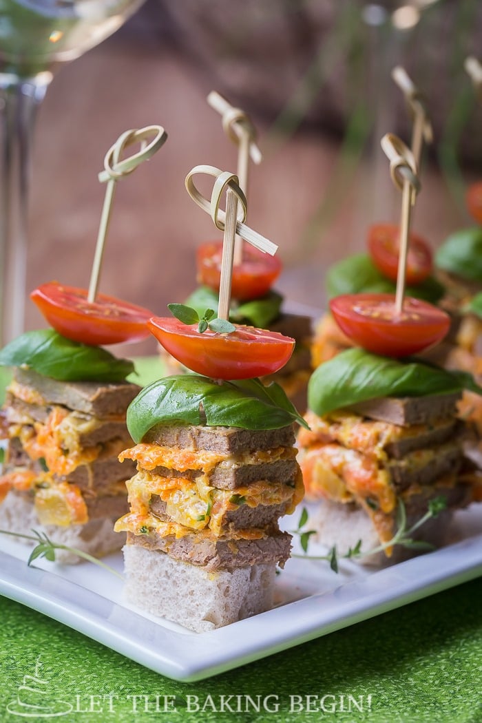 Chicken stacks with tomatoes on a white decorative plate.