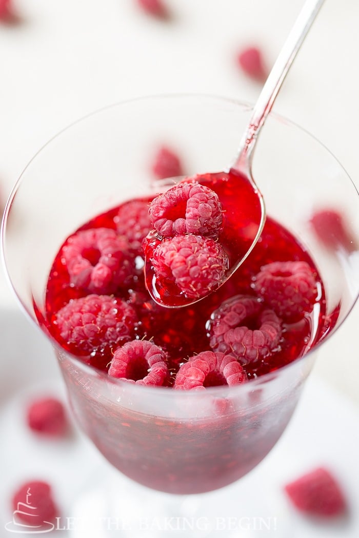 Raspberry jam with fresh raspberries in a cup with a spoon.