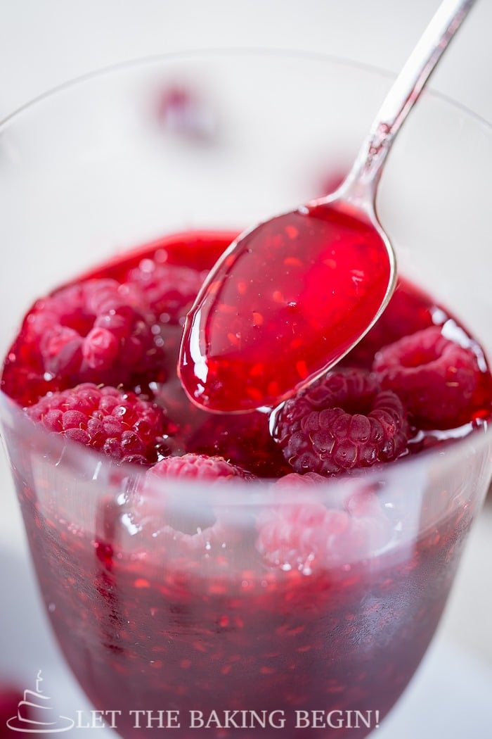 Sweet raspberry jam in a cup with a spoon.
