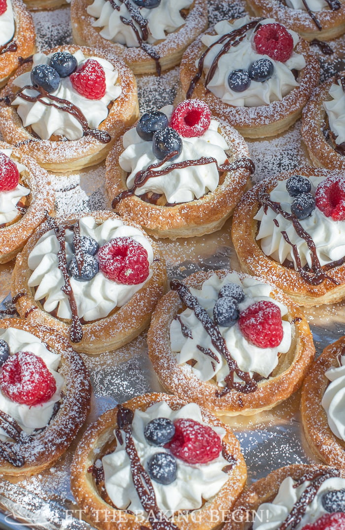 Puff pastry tarts topped with a delicious sweet cream topped with fresh berries and sprinkled with powdered sugar. 