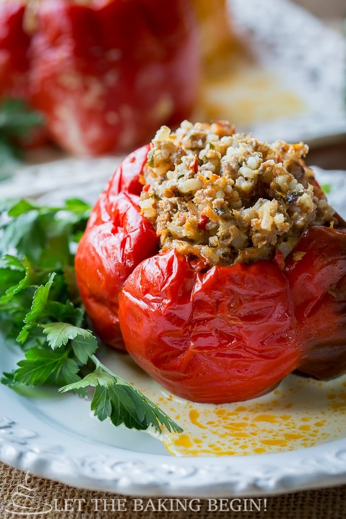 Stuffed red pepper on a white decorative plate with fresh greens.