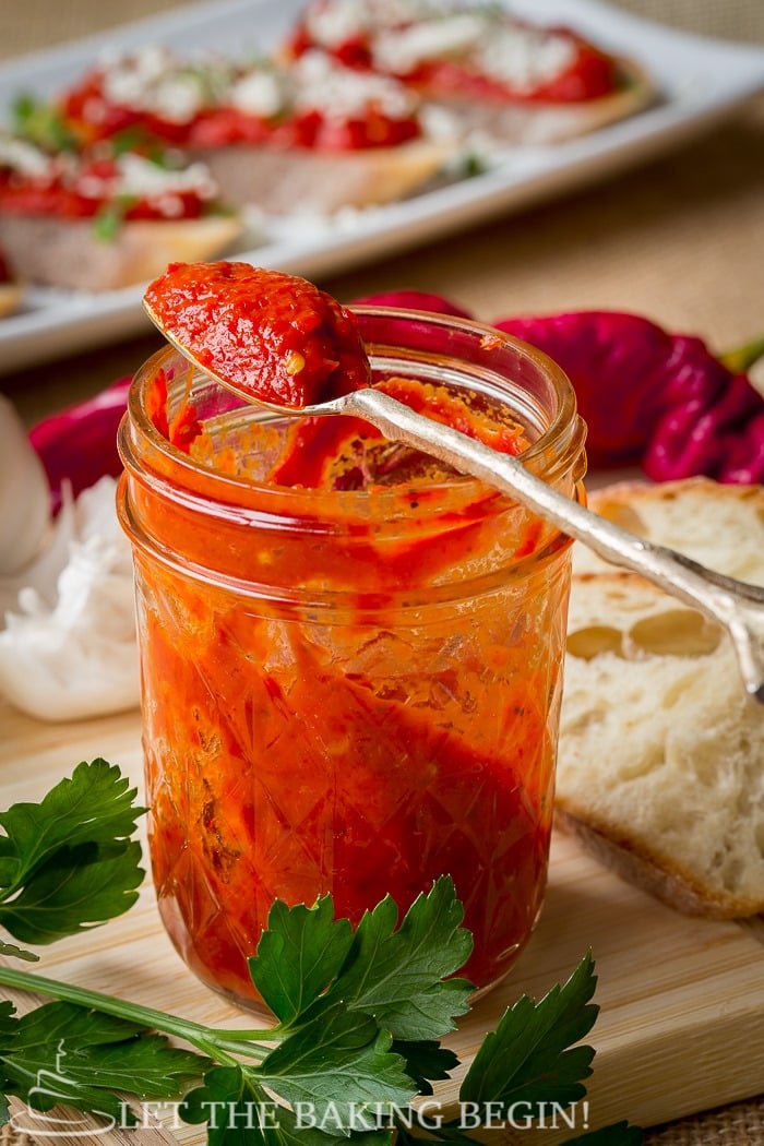 Spicy roasted pepper dip in a mason jar with a metal spoon.