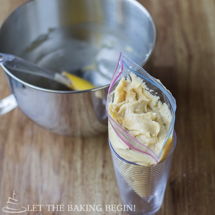 French almond cream in a Ziploc bag in a cup, next to the mixing bowl.