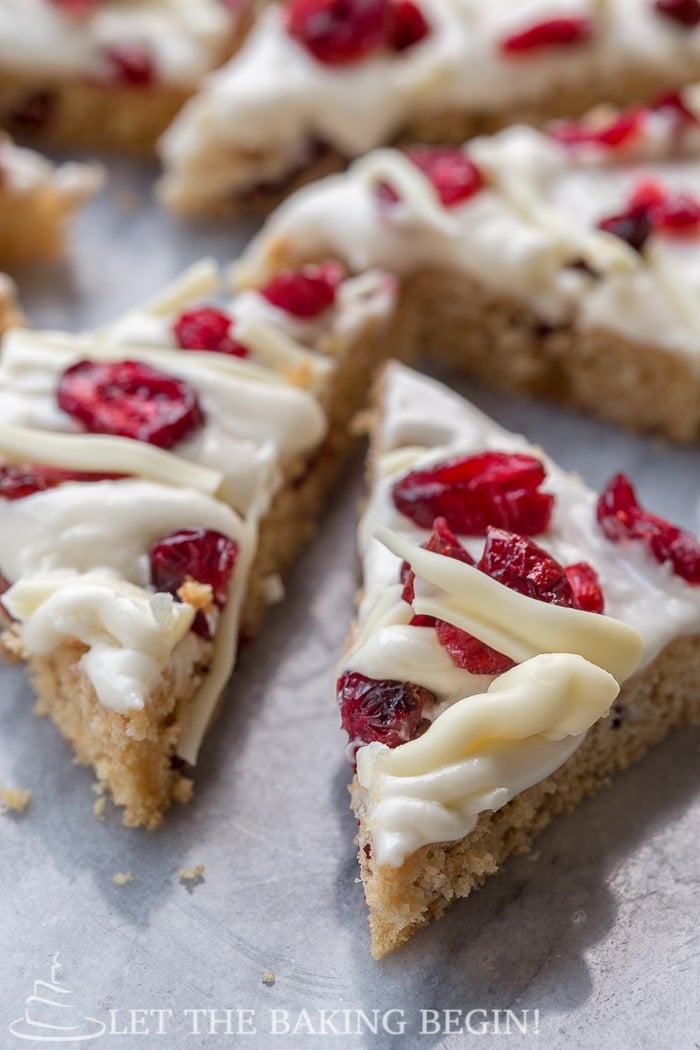 Cranberry bliss bars topped with dried cranberries on a platter.