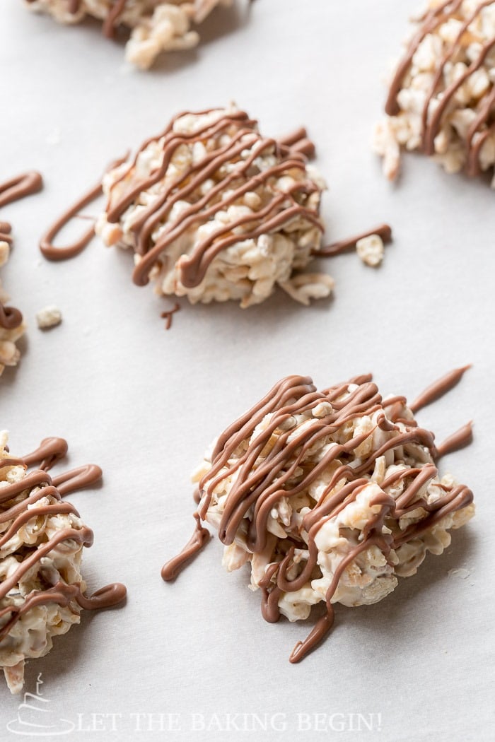 Close up picture of a no bake rice krispies cookie drizzled with chocolate on a white table. 