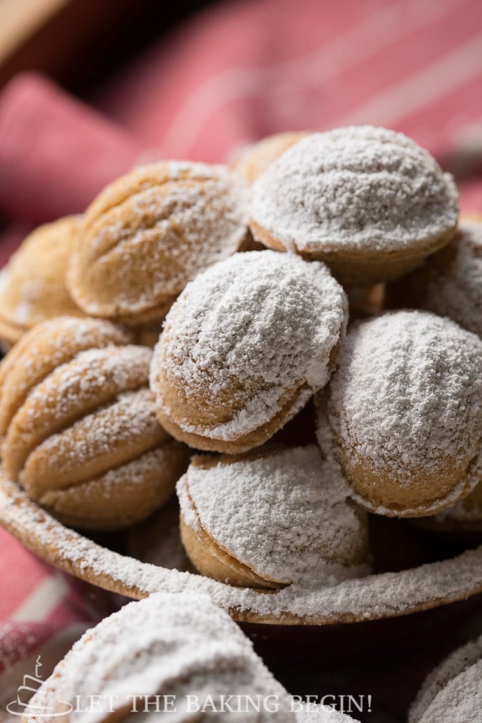 Oreshki in a bowl topped with powdered sugar. 