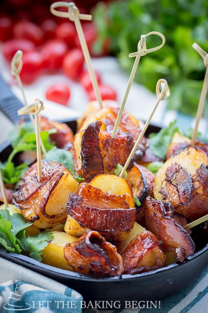 Potatoes wrapped in bacon pieces with toothpicks in a black bowl. 