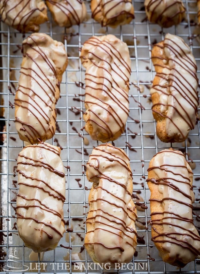 Maple glazed coffee eclairs on a cooling rack drizzles with chocolate.