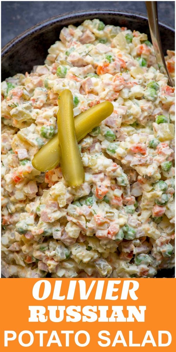 Olivier Salad in a bowl with a spoon topped with pickle slices. 