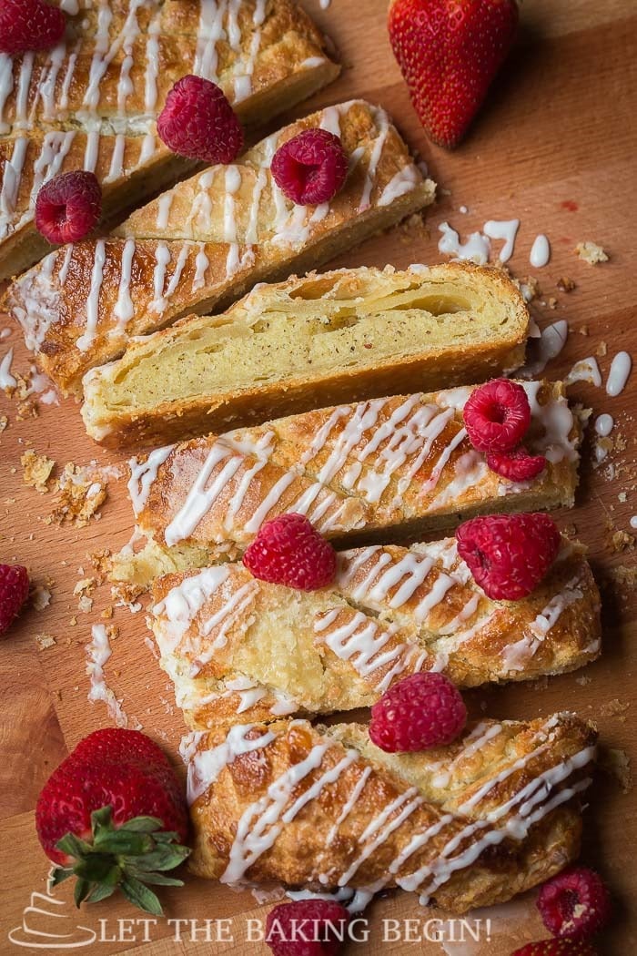 Sliced puff pastry braid topped with powdered sugar glaze and raspberries.
