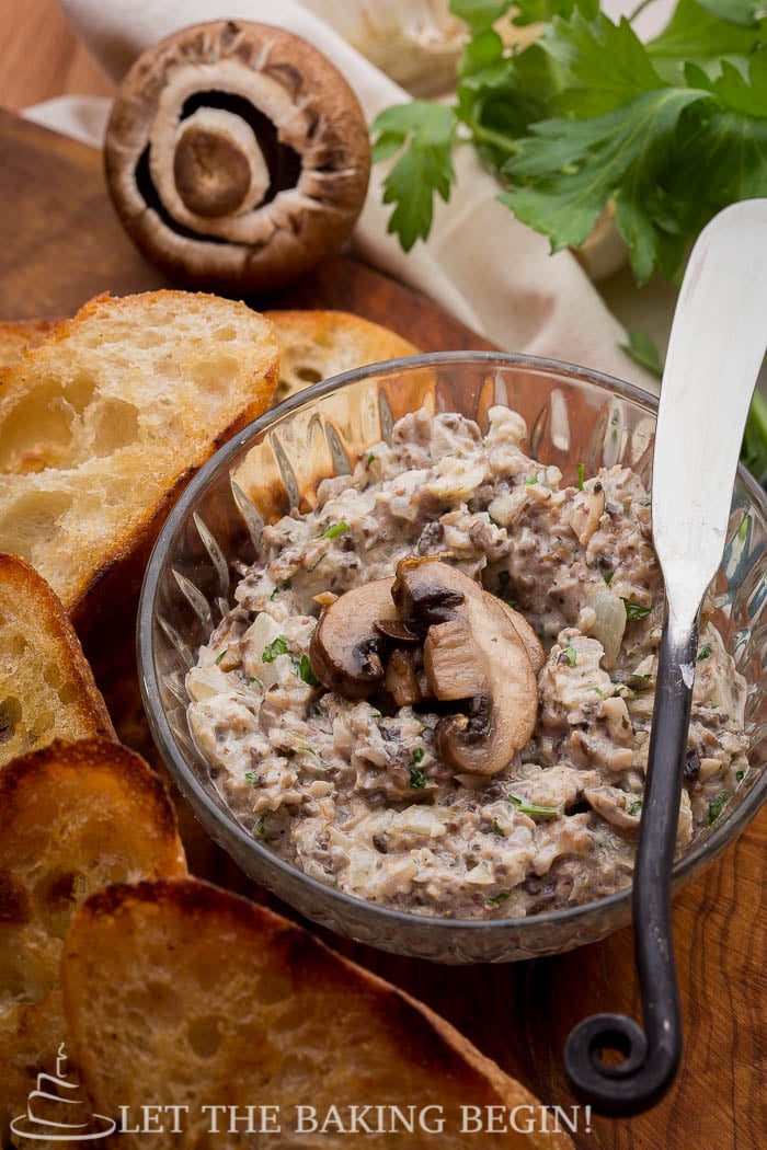 Mushroom pate made with toasted pine cones, in a glass bowl with sliced baguette