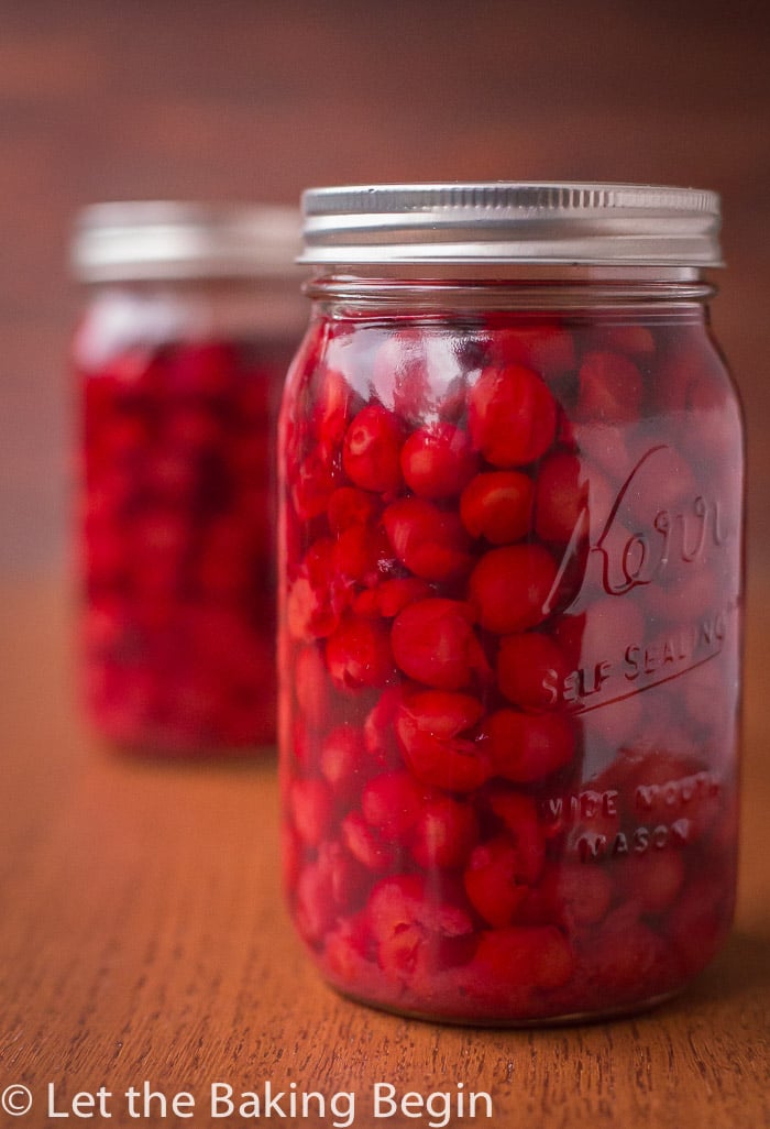 Close up picture of canned cherries in a mason jar on a counter top.