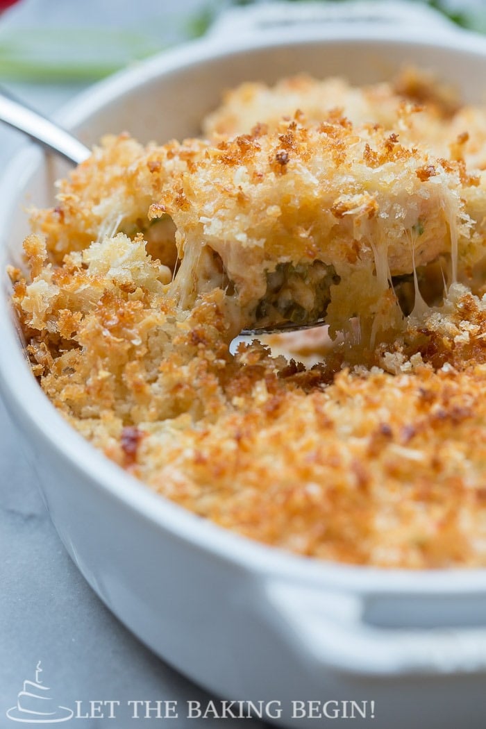 Cheesy Parmesan Crusted Salmon Bake in a casserole dish with a spoon.