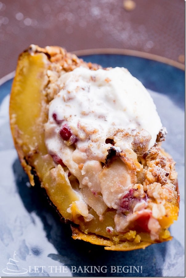 A slice of acorn squash with an apple and cranberry filled topped with whipped cream. 