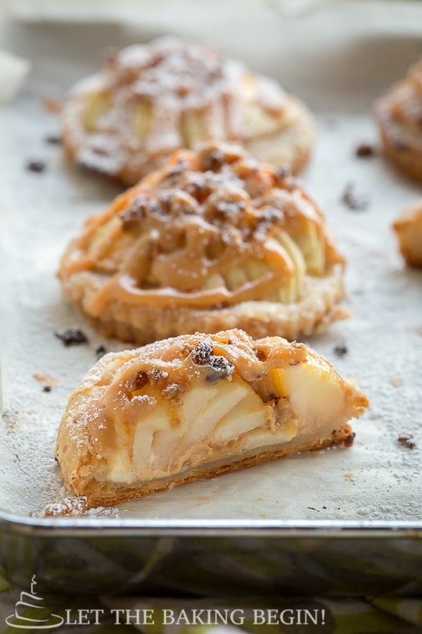 Puff pastries filled with apples and dulce de leche on a baking sheet. 