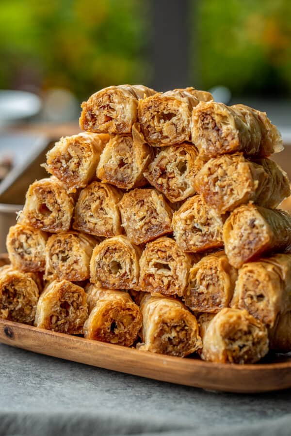 A stack of baklava rolls on a plate, side view.