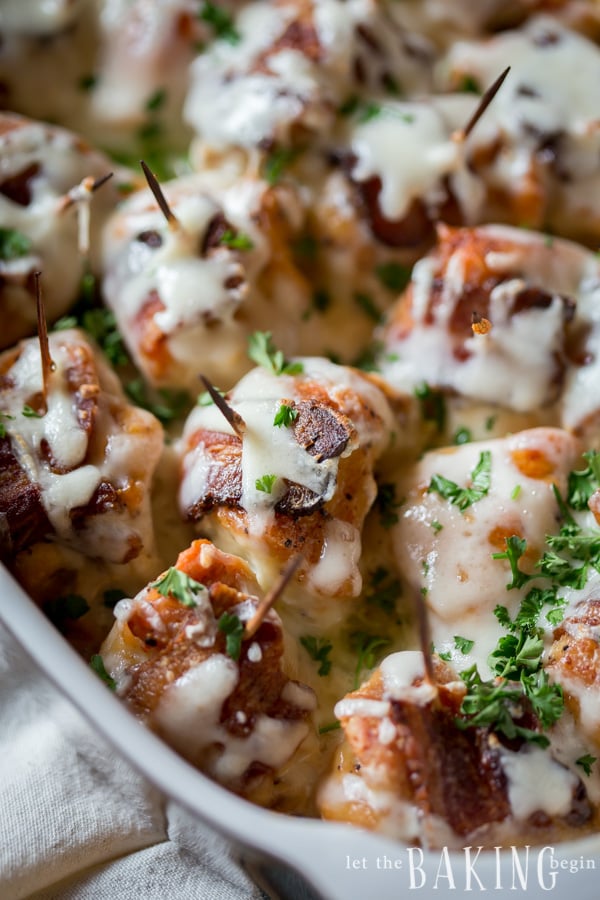 Cheesy Bacon Wrapped Chicken topped with a creamy sauce and cheese. Garnished with herbs and served great with a side of mashed potatoes.