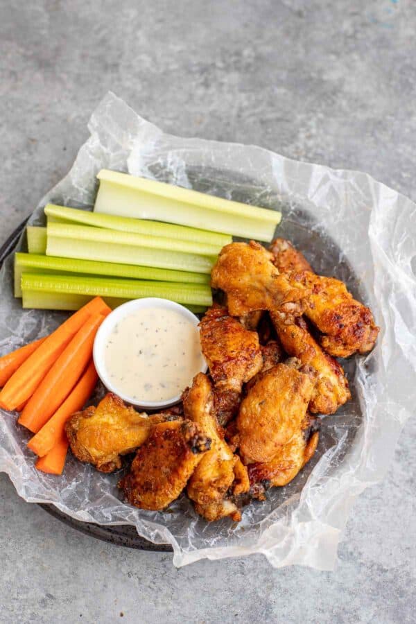 Ranch Wings set on a plate with carrot sticks, celery and ranch.