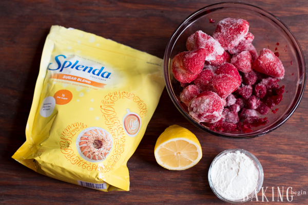 Splenda bag, lemon , frozen strawberries and raspberries in a bowl, and cornstarch in a bowl on a table.