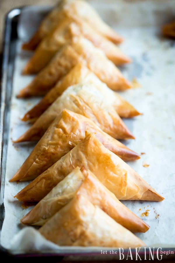 Spinach and feta phyllo triangles laid out on a baking sheet. 