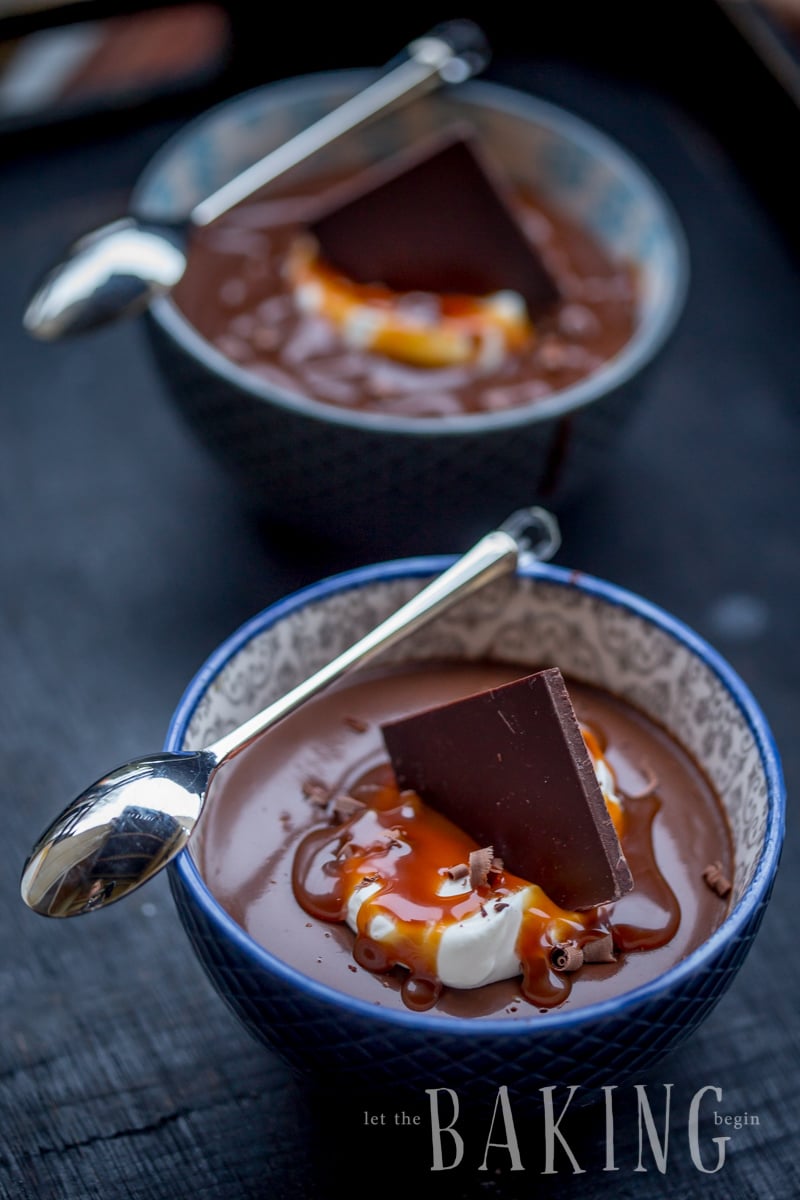 Two bowls of chocolate pot de creme with chocolate squares on top