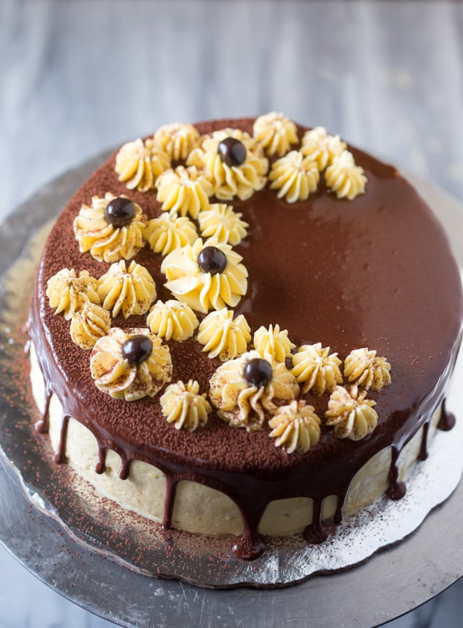 Chocolate cake with a custard buttercream topped with chocolate ganache with decoration on top of the cake. 