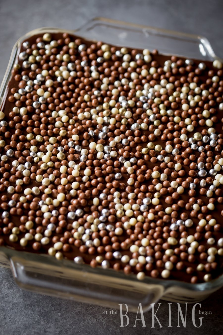 Top view of cake topped with pearls in a baking pan.