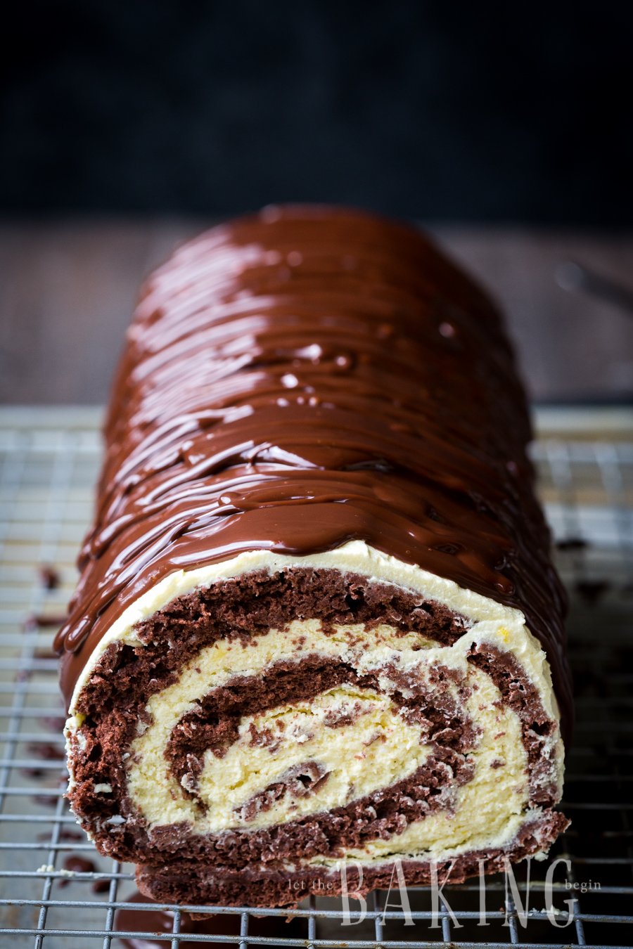 Chocolate custard roll on a cooling rack topped with chocolate ganache. 