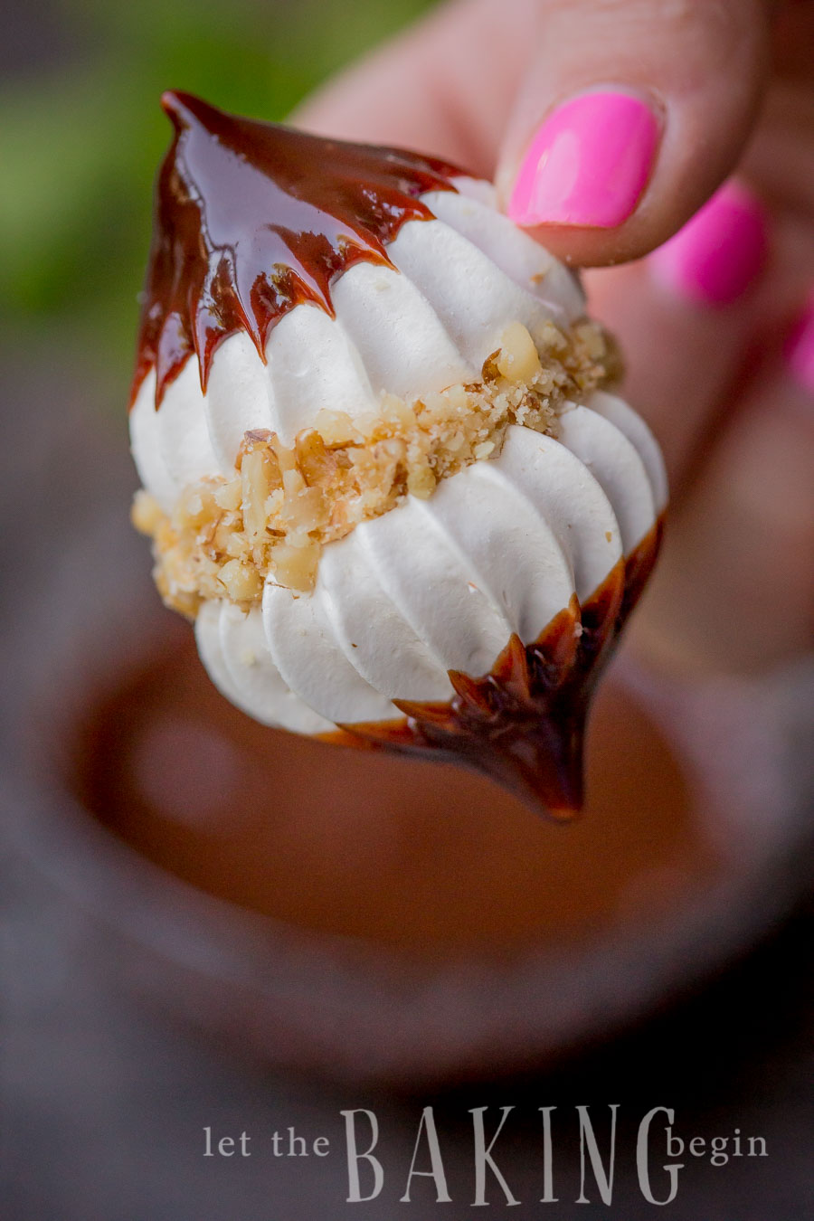 Hazelnut Meringue Bomb dipped in a chocolate ganache in hand.